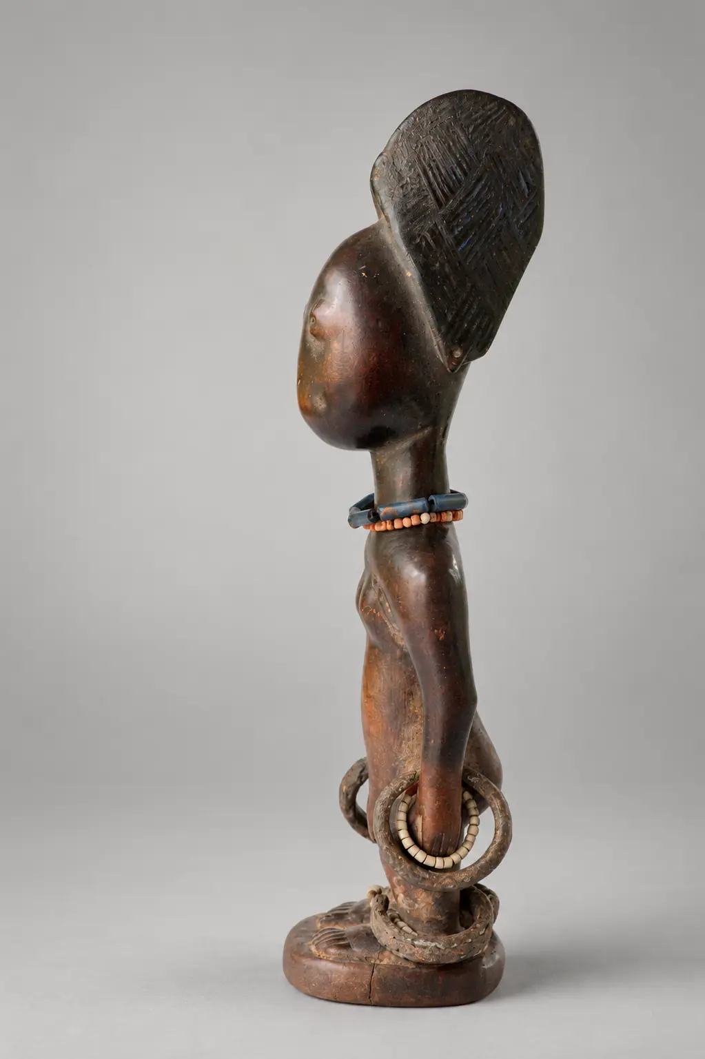 Profile view of an Ere Ibeji highlighting coiffure, body proportions and carved ornament