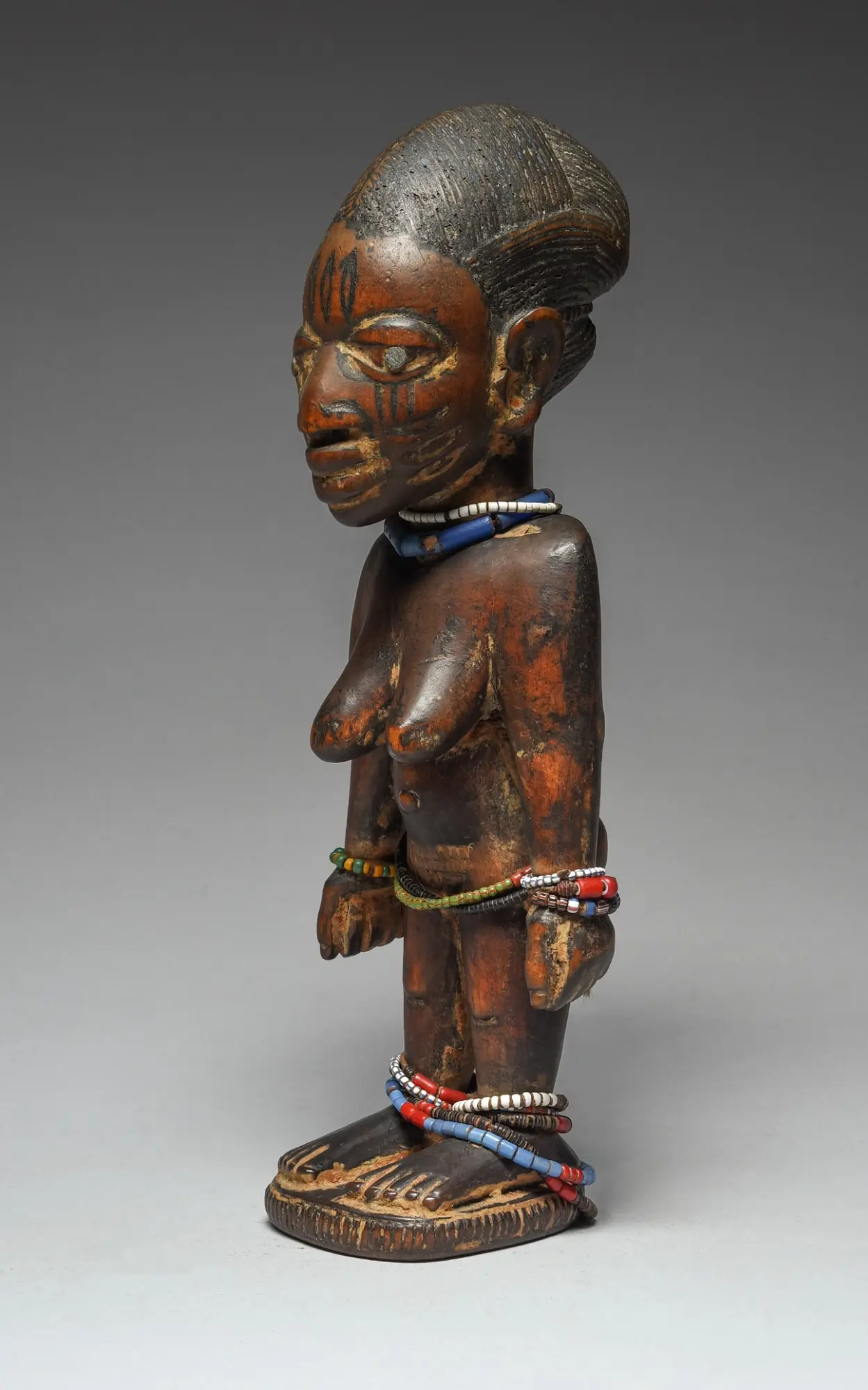 Adorned female Ere Ibeji with layered bead ornaments